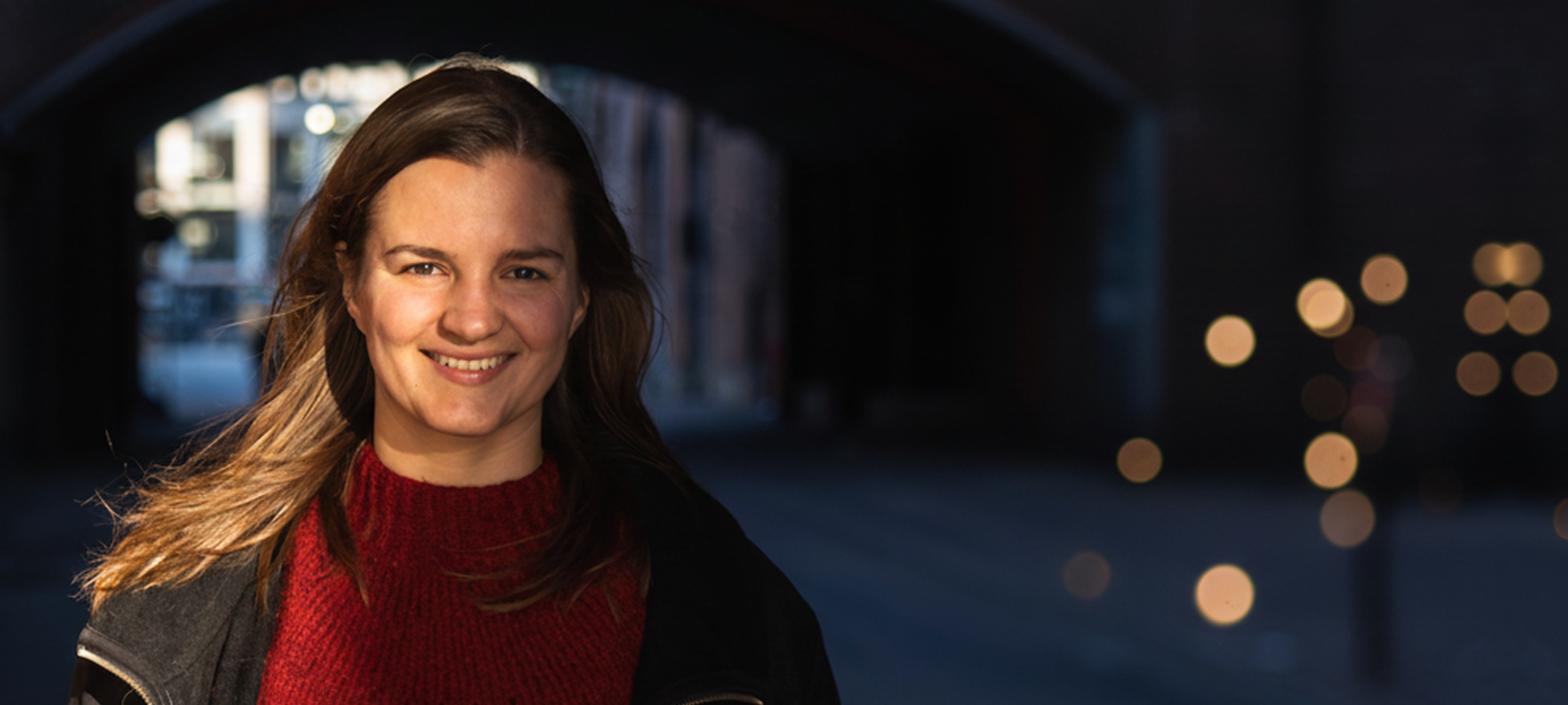 Anne Clara Laugesen, Photoncycles danske General Manager, smiler udendørs i skumringen med sløret baggrundsbelysning.